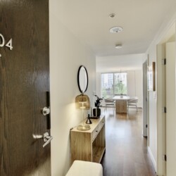 Door with 504 plaque opens to a bright hallway leading to a dining nook and living area in a modern apartment.