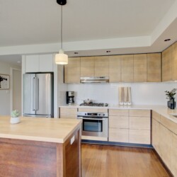 Modern kitchen with wood cabinets, stainless steel appliances, white tile backsplash, and an island centerpiece.