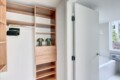 Open closet with tall wooden shelves and drawers, two green ribbed lamps on a shelf, and a doorway to a bright bathroom.