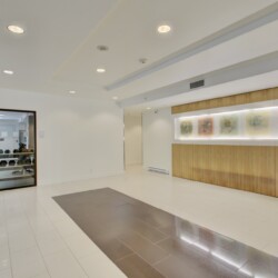 Modern building lobby with a long wooden reception desk and backlit abstract art panels on the wall