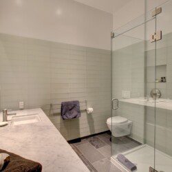 Contemporary bathroom with a double-sink vanity, marble countertop, and a glass-enclosed shower.