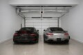 Black Porsche 911 Turbo S and silver Mercedes-AMG GT parked side by side in a clean, empty garage.
