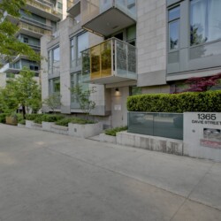 Modern residential building with glass balconies along a tree-lined street; sign reads 1365 Davie Street in front.