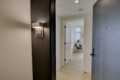 Open doorway into a bright living area; hallway with a dark wall and apartment number 606 plaque visible next to a lighted wall sconce by the door.