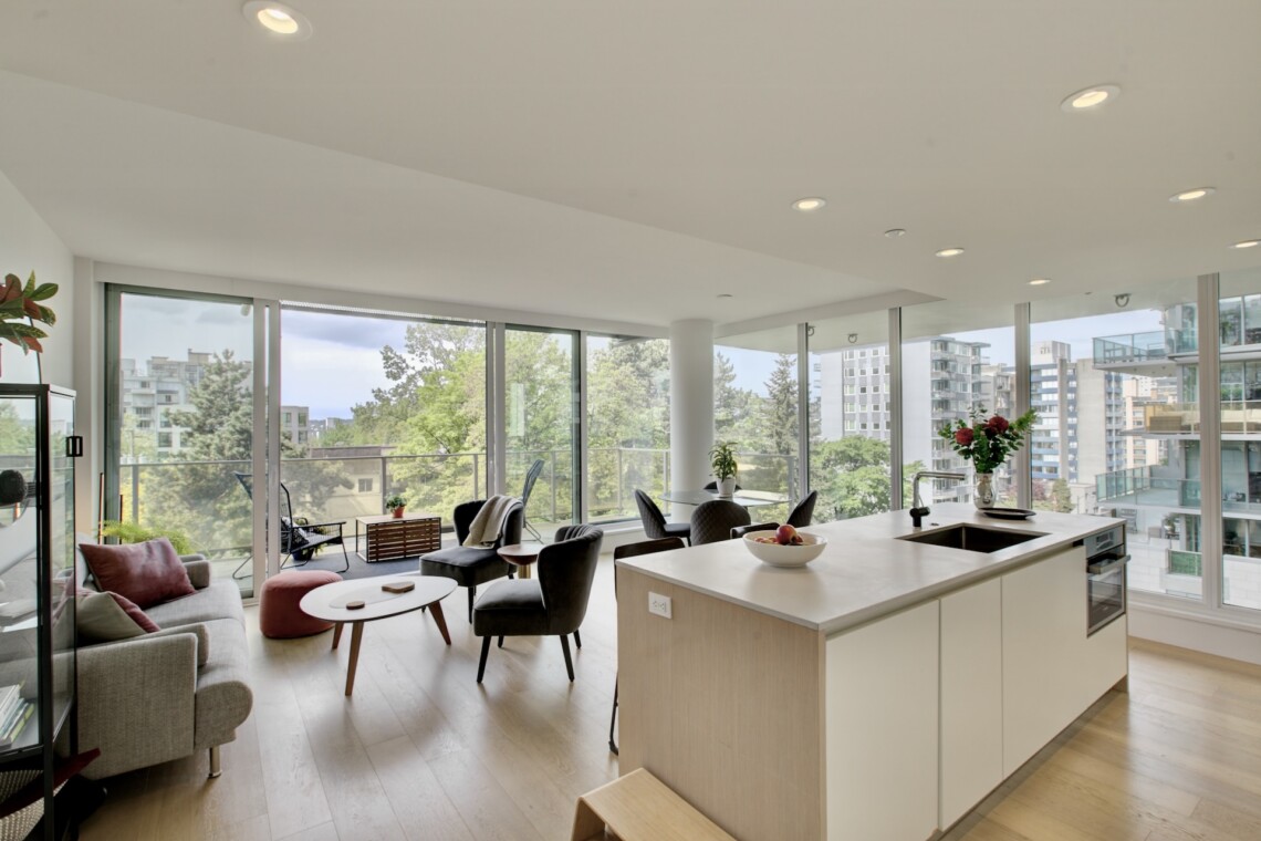 Bright open-concept living area and kitchen with floor-to-ceiling windows and a cityscape view.