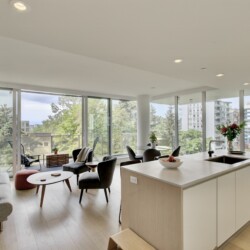Bright open-concept living area and kitchen with floor-to-ceiling windows and a cityscape view.