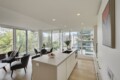 Bright open-concept kitchen and living area with large floor-to-ceiling windows and cityscape views behind a modern island.