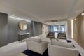Modern hotel lobby with gray walls, circular wall mirror, and gray seating area facing a mural.