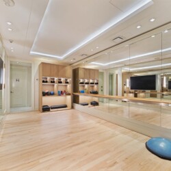 Well-lit boutique fitness studio with wooden floors, wall mirrors, and stacked exercise balls on the right.