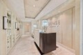 Reception area of Sense Rosewood Spa with a dark curved front desk and crystal lamp centerpiece, marble floors, and glass display cabinets on the left.
