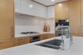 Contemporary kitchen with white countertops and an island sink, surrounded by wooden cabinets and built-in appliances.