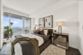 Bright, modern bedroom with a large balcony window, brown bedding, and two abstract framed paintings above the bed.