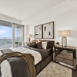 Bright, modern bedroom with a large balcony window, brown bedding, and two abstract framed paintings above the bed.