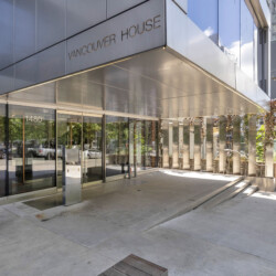 Front view of a modern glass-and-metal building with 'Vancouver House' on the facade and a glass entryway toward the street.