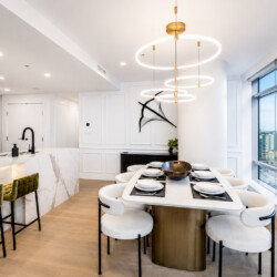 Open-concept kitchen and dining area with marble island, circular pendant lights, and large windows overlooking the city.