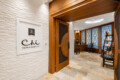 Wooden doorway opens to a spa reception with a desk, chairs, and a curved rug.