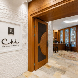 Wooden doorway opens to a spa reception with a desk, chairs, and a curved rug.