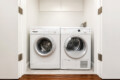 White front-loading washing machine and dryer side by side in a compact laundry closet with white upper cabinets above them