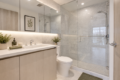 Contemporary bathroom with a double-sink vanity, plants, and a glass-enclosed shower with chrome fixtures.