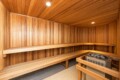 Wood-paneled sauna with long benches along two walls and a heater with rocks in the corner.