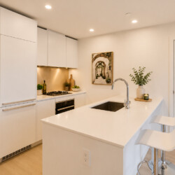 Bright modern kitchen with white cabinets, an island sink, and two white bar stools.