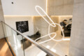 Modern interior lobby with a large glowing abstract neon sculpture hanging above a glass railing and polished floor.