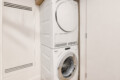 Stacked front-loading washing machine below a clothes dryer in a narrow laundry closet.