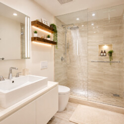 Modern bathroom with a double-sink vanity, backlit mirror, and a glass-enclosed shower with a rainfall showerhead; beige tiles and white towels with brown stripes.