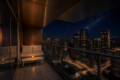 Night city view from a balcony with a beige outdoor sofa and candlelight, overlooking a lit downtown skyline at night.