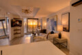 Sunset view through large windows into a modern living room with a white sofa and abstract art.