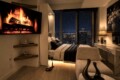 Modern bedroom at night with a lit fireplace displayed on a wall-mounted TV and a bed by a window overlooking a city skyline.