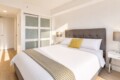 Bright hotel bedroom with a large gray upholstered bed, white linens, and a yellow accent pillow.1823757?