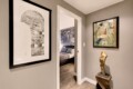 Hallway with two framed artworks and a wood sculpture beside an open doorway to a bedroom.
