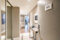 Entry hallway of a modern apartment with a console table, blue vase, and wall art leading to a lit interior room (803 door placard)
