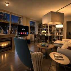 Cozy modern living room at night with a fireplace, large windows showing the city skyline, and a white sectional sofa.