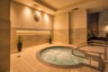 Indoor spa area with a circular bubbling hot tub, beige tiled floor, and soft overhead lighting.
