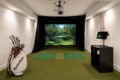 Indoor golf simulator room with a screensled virtual course, hitting mat, and projector above.