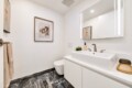 Minimalist white bathroom with a wide rectangular sink, two-handle faucet, backlit mirror, and marble-patterned floor.