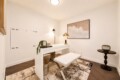 White modern home office with a sleek desk, bench seating, and a framed wave artwork on the wall