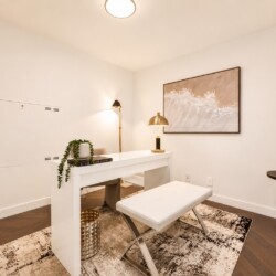 White modern home office with a sleek desk, bench seating, and a framed wave artwork on the wall