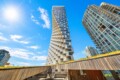 Modern high-rise buildings under a bright blue sky with a low wooden walkway in the foreground.
