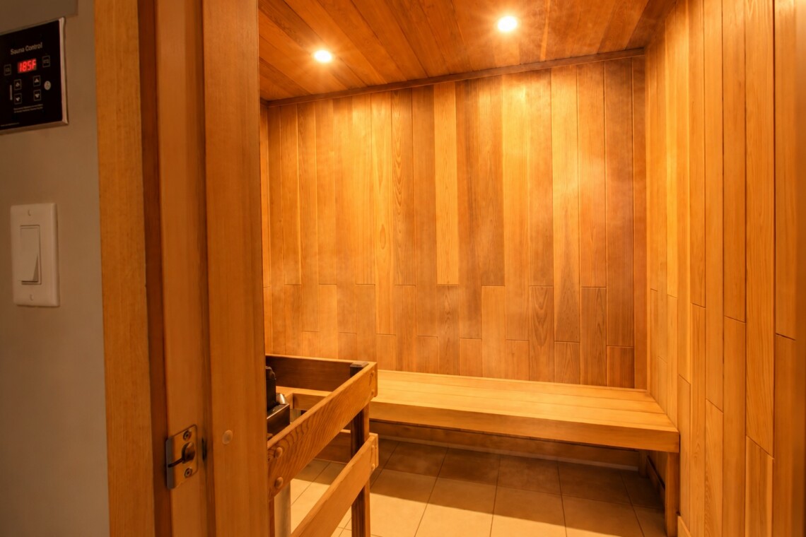 Wood-paneled sauna interior with long benches along the walls and warm overhead lighting.