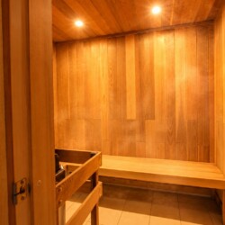 Wood-paneled sauna interior with long benches along the walls and warm overhead lighting.