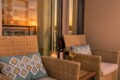 Cozy balcony seating with wicker chairs, blue patterned cushions, a candle, wine bottle and two glasses at sunset.