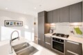 Modern kitchen with gray cabinetry, white countertops and a stainless steel double-basin sink on an island.