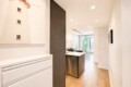 Open-concept kitchen and living area with white cabinetry, a stainless dishwasher, dark island, and lighthouse artwork on the wall.