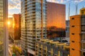 Sunset light reflecting off glass apartment towers in a modern cityscape.