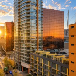 Sunset light reflecting off glass apartment towers in a modern cityscape.
