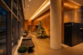 Modern hotel lobby with a tall christmas tree, warm golden lighting, and a black tufted bench by glass walls.