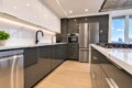 Modern kitchen with white upper cabinets, gray lower cabinets, black faucet, marble backsplash, and stainless steel appliances.